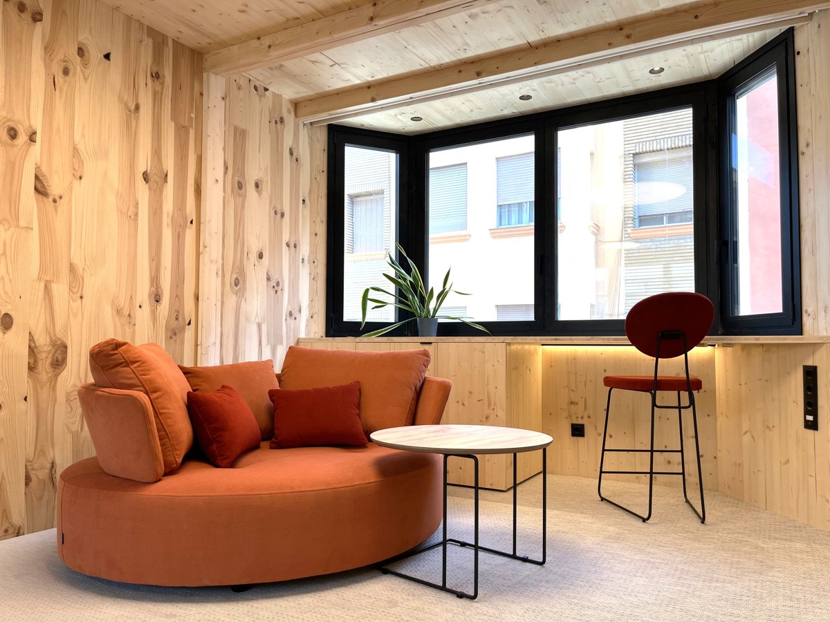 Salón de una suite con revestimientos de madera y un gran ventanal